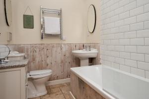 een badkamer met een wastafel, een toilet en een ligbad bij Hexham Cottage by Coast & Country Stays in Seahouses
