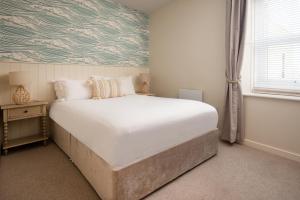 een slaapkamer met een groot wit bed en een raam bij Hexham Cottage by Coast & Country Stays in Seahouses