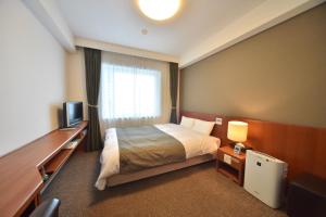 a hotel room with a bed and a television at Dormy Inn Wakkanai in Wakkanai