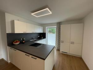 a kitchen with white cabinets and a black counter top at Ferienwohnung Zirbenduft in Wertach +3 photos