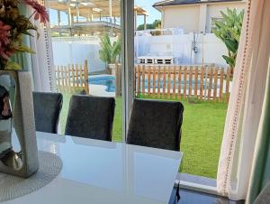a white table and chairs with a view of a yard at Chalet con jardin privado y piscina para disfrutar con la familia y amigos in Punta Umbría