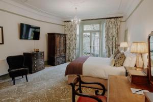 a bedroom with a bed and a desk and a window at The William Cecil in Stamford