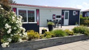 a house with a deck with a table and chairs at Chalet Olm Ferienpark Olmenduin Zeeland 4 Pers familienfreundlich Hunde willkommen in Serooskerke