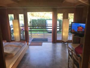 a living room with a couch and a tv and a balcony at Ferienhaus Blockhaus by Seeblick Ferien Edersee in Waldeck