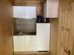 a small kitchen with white cabinets and a sink at Ferienhaus Blockhaus by Seeblick Ferien Edersee in Waldeck +8 photos
