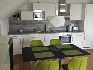a kitchen with a black table and green chairs at Fewo Reeder's Topp by Seeblick Ferien ORO, Penthouse,Panoramablick,Sauna in Olpenitz