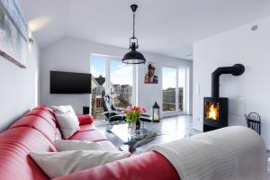 a living room with a red couch and a fireplace at Fewo Kapitän James Cook by Seeblick Ferien ORO, Wasserbett, E-Ladesäule, in Olpenitz
