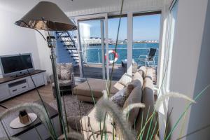 ein Wohnzimmer mit einem Sofa und Blick auf das Wasser in der Unterkunft Schwimmendes Ferienhaus Antares One by Seeblick Ferien ORO, rundum Wasser, Sauna in Olpenitz