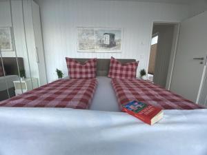 ein Bett mit zwei Kissen und ein Buch darauf in der Unterkunft Schwimmendes Ferienhaus Antares One by Seeblick Ferien ORO, rundum Wasser, Sauna in Olpenitz