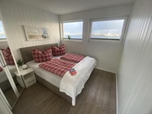 ein kleines Schlafzimmer mit einem Bett mit roten Kissen in der Unterkunft Schwimmendes Ferienhaus Antares One by Seeblick Ferien ORO, rundum Wasser, Sauna in Olpenitz