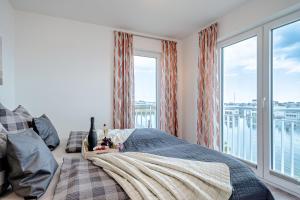 ein Schlafzimmer mit einem Bett und einem großen Fenster in der Unterkunft Schleivilla Lootsen Hus by Seeblick Ferien ORO, 3Etagen,8Pers,Sauna,Kamin in Olpenitz