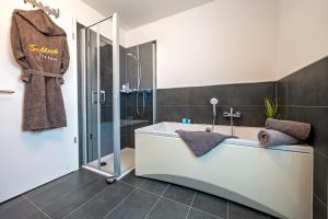 ein Badezimmer mit Badewanne und Dusche in der Unterkunft Schleivilla Lootsen Hus by Seeblick Ferien ORO, 3Etagen,8Pers,Sauna,Kamin in Olpenitz