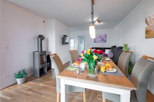 a dining room and living room with a table with flowers at Fewo MEERwert by Seeblick Ferien ORO, Familienfreundlich, Sauna, Kamin,XL Dusche in Olpenitz