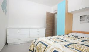 a white bedroom with a bed and a dresser at Gelsomino in Marina di Campo