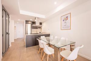 eine Küche und ein Esszimmer mit einem Glastisch und weißen Stühlen in der Unterkunft Sweett - Harmony Central in Barcelona
