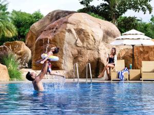 a man holding a child in the water in a swimming pool at Novotel Hyderabad Convention Centre in Hyderabad