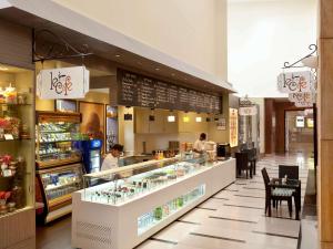 a restaurant with a counter with people preparing food at Novotel Hyderabad Convention Centre in Hyderabad