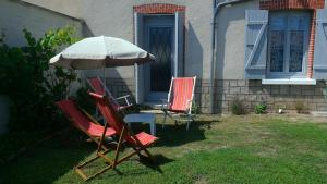 two chairs and an umbrella in front of a house at Le Francvillois in Villefranche-Sur-Cher