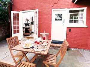a wooden table with plates of food on a patio at Hidden Cottage by The Suffolk Cottage Collection in Aldeburgh