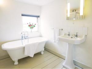 a white bathroom with a tub and a sink at Hidden Cottage by The Suffolk Cottage Collection in Aldeburgh +15 photos