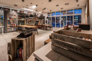 eine Bibliothek mit Tischen, Stühlen und Bücherregalen in der Unterkunft Arkadenhaus - Hotel Freiherr von Schwarzenberg in Papenburg