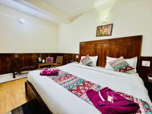 una camera da letto con un grande letto con accappatoi viola di Silver Land with mountain view - A River side property a Manāli