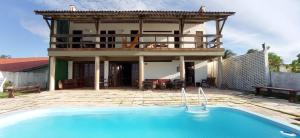 une maison avec une piscine devant une maison dans l'établissement Casa Jangada - Incrível vista mar com Piscina e a melhor localização na Beira Mar da Taíba, à Taíba