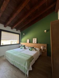 a bedroom with a large bed with a green wall at Casas Rurales LA HUERTA DEL CURATO I in Tolbaños