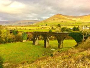 a bridge in a field with hills in the background at Railway cottage Annascaul in Anascaul +8 photos