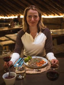 a woman sitting at a table with a plate of food at Eventyrhyttene i Jotunheimen in Stuttgongfossen +11 photos