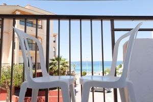 2 weiße Stühle auf einem Balkon mit Blick auf den Strand in der Unterkunft Vibra Calima Apartamentos - Adults only in Sant Antoni de Portmany