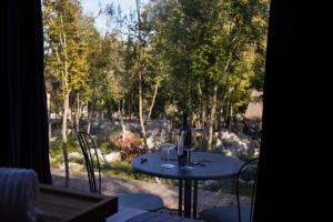 a table with two wine glasses on it on a patio at Oblun Eco Resort - Mirror Cabin in Podgorica