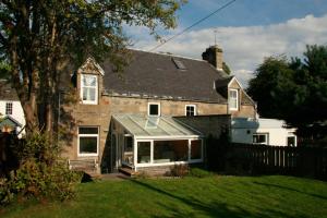 a house with a conservatory on the front of it at Carrick House in Kingussie