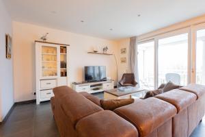 a living room with a brown couch and a tv at Duinhof VIII D201 in Cadzand