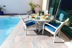 a table and chairs on a patio next to a pool at Villa ArenaMar with private Pool in Playa del Ingles