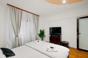 a bedroom with a white bed and a television at Ultracentral Apartment Braila in Brăila