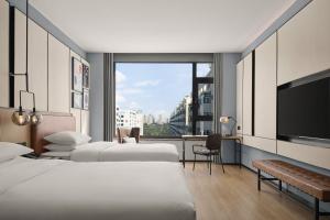 a hotel room with two beds and a flat screen tv at Four Points by Sheraton Datong Pingcheng in Datong