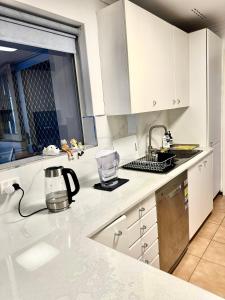 a kitchen with white cabinets and a counter top at Cozy room near CBD airport in Perth