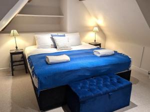 una camera da letto con un letto grande con una coperta blu di West Pallant Georgian Townhouse in City Centre with Courtyards, BBQ & Log Burners - Dogs Welcome! Chichester Holiday Properties a Chichester