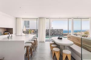 a kitchen with white counters and stools and windows at LuxLiving Tenerife Villa Balansa in Adeje