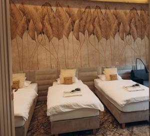 a room with two beds and a wall with feathers at KOLUMNA HOUSE dom noclegowy z sauną i balią in Łask