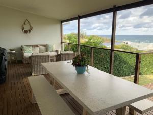 a living room with a table and a view of the ocean at The G Shack at Rennies Beach in Ulladulla