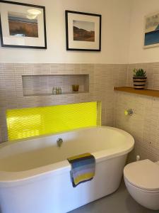 a bathroom with a white tub and a toilet at Eco Friendly beach house in Camber +12 photos
