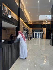 a person in a robe standing at a counter in a lobby at Nasamat Hotel in Medina