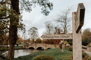 a wooden sign in a park with a bridge at The Swan Hotel in Bibury
