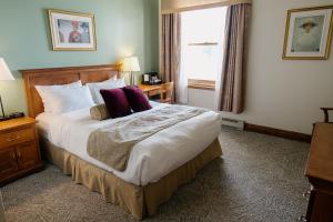 ein Hotelzimmer mit einem großen Bett und lila Kissen in der Unterkunft Hotel Tadoussac in Tadoussac + 21 Fotos