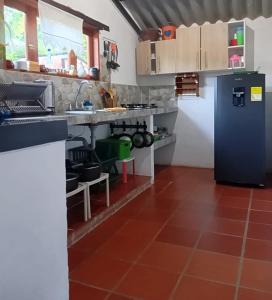 a kitchen with a blue refrigerator and a red tile floor at Alojamiento Villa Dani in Villa de Leyva