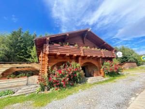 a log cabin with flowers on the side of it at Hanul Prislop in Statiunea Borsa