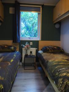 two beds in a room with a window at Chalet Relax in Putten