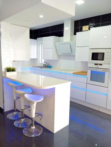 a kitchen with white cabinets and bar stools at Chalet con jardin privado y piscina para disfrutar con la familia y amigos in Punta Umbría